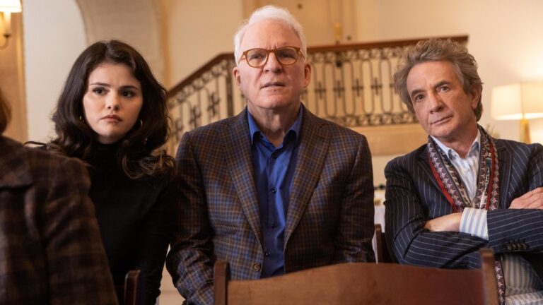 Three main characters seated together in a tense moment from a cozy mystery series, capturing the investigative tone of cozy mystery shows like Only Murders in the Building.