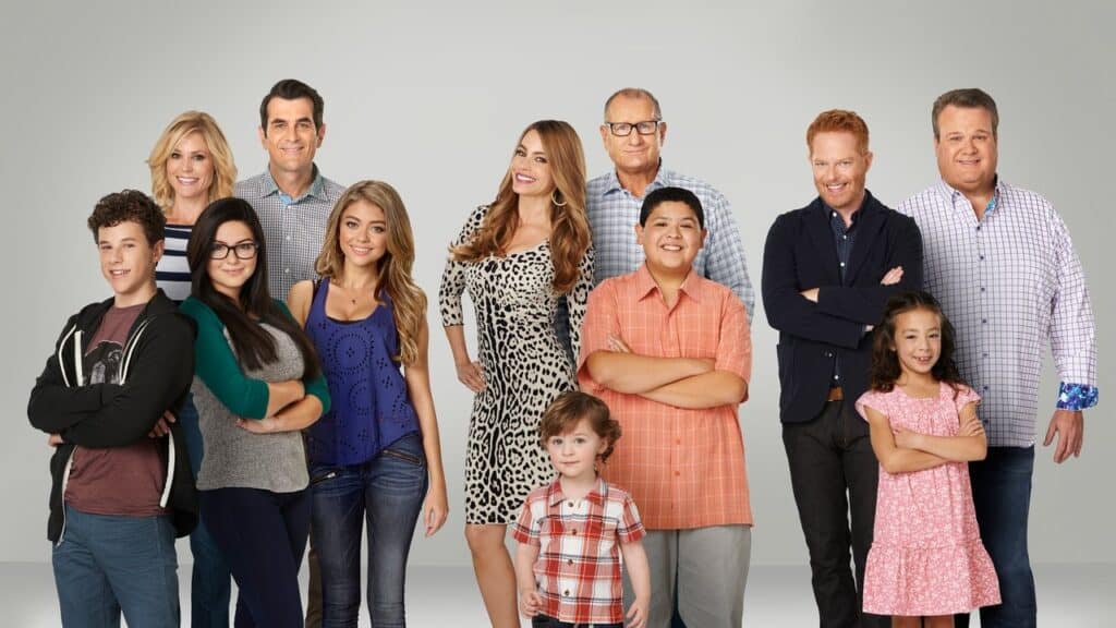Large ensemble cast standing together in a lighthearted family portrait, capturing the humor and relationships of shows like Modern Family that actually match.