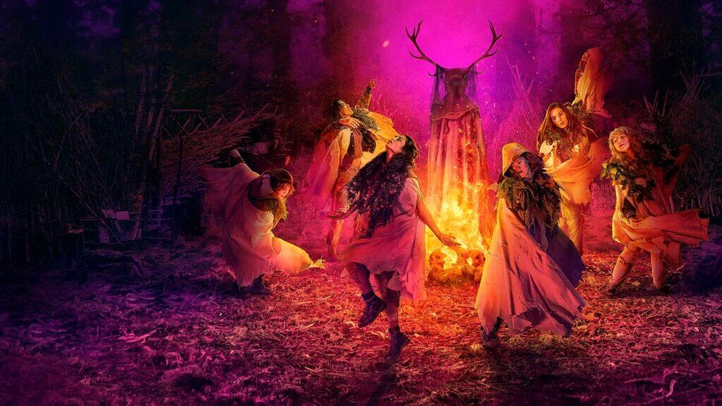 Group of women performing a ritual around a fire in a dark forest, capturing the eerie survival tension of survival thriller shows like Yellowjackets.