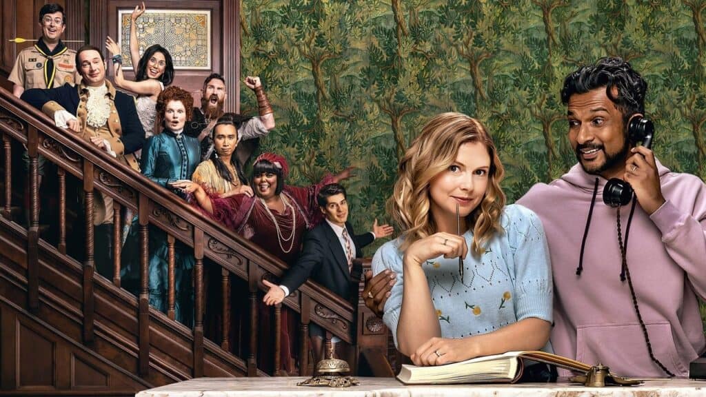 The ghosts crowd the staircase behind the living couple, each reacting differently as the pair stand in the foreground inside the mansion.