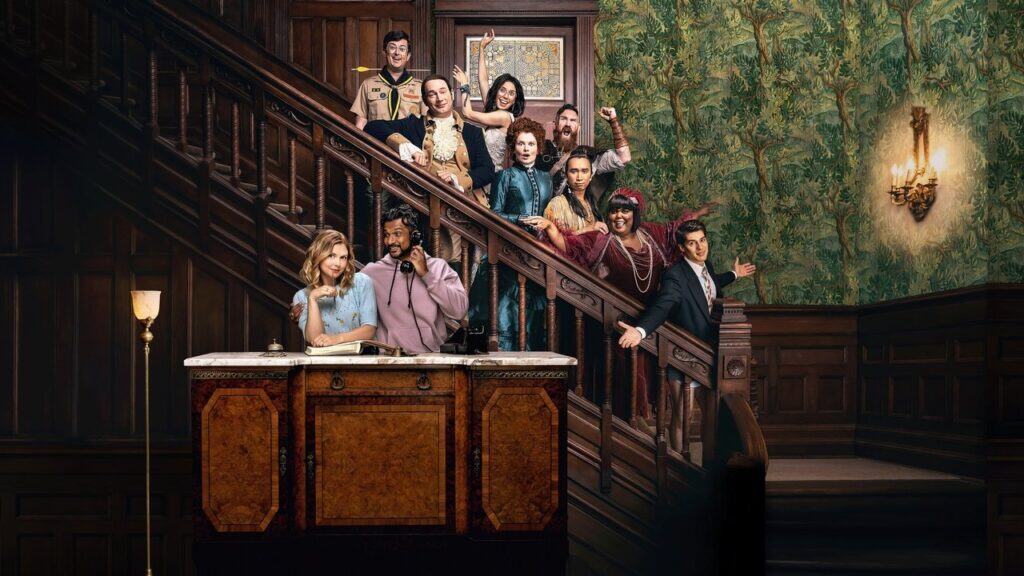 A wide shot of the ghosts lining the staircase while the living couple sit below, emphasizing the crowded and chaotic household dynamic.