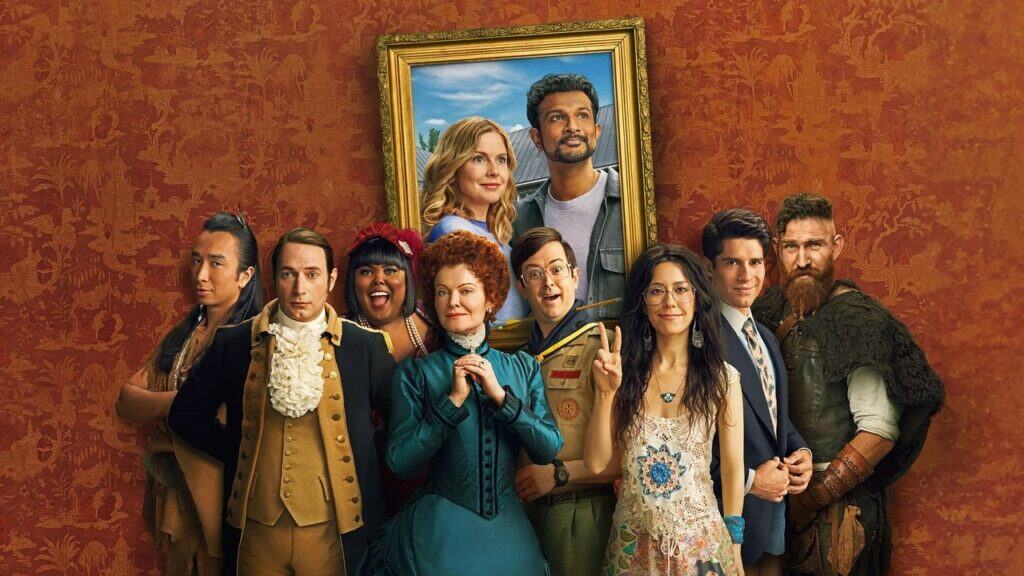 The ghosts stand together beneath a framed portrait of the living couple, visually blending past and present inside the mansion.