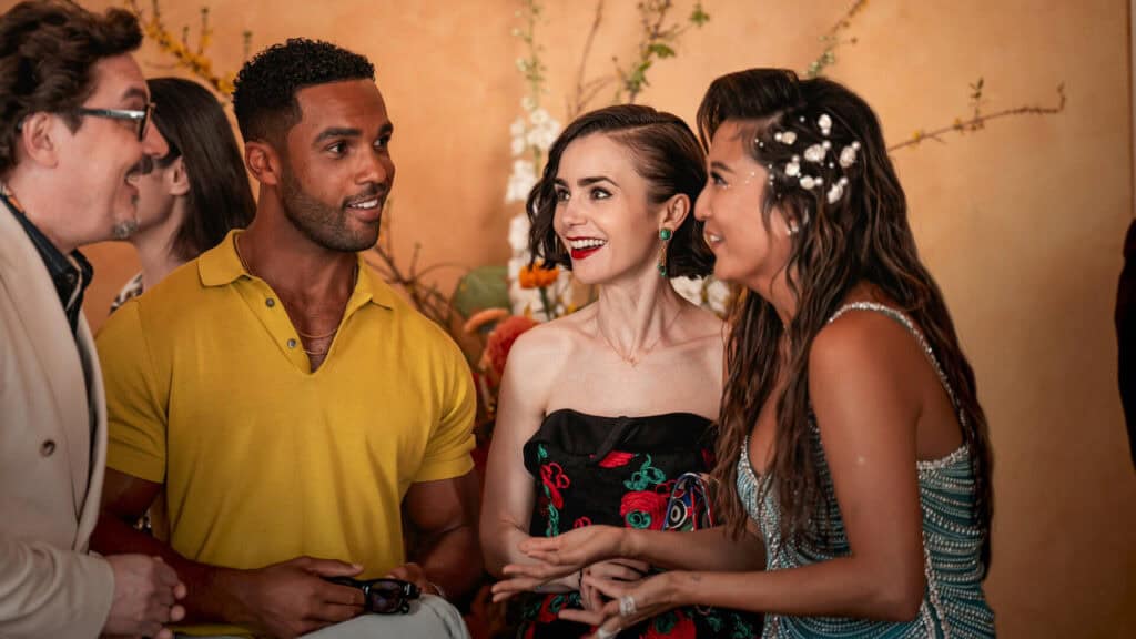 A group of well-dressed people talking and laughing together at an elegant indoor event.