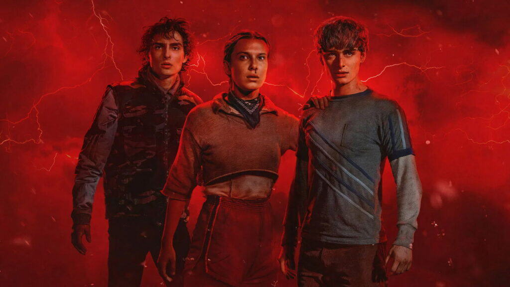 Three teens stand together against a red, lightning-filled background as supernatural danger looms in Stranger Things.
