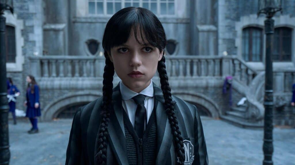 Wednesday Addams standing alone in her Nevermore Academy school uniform