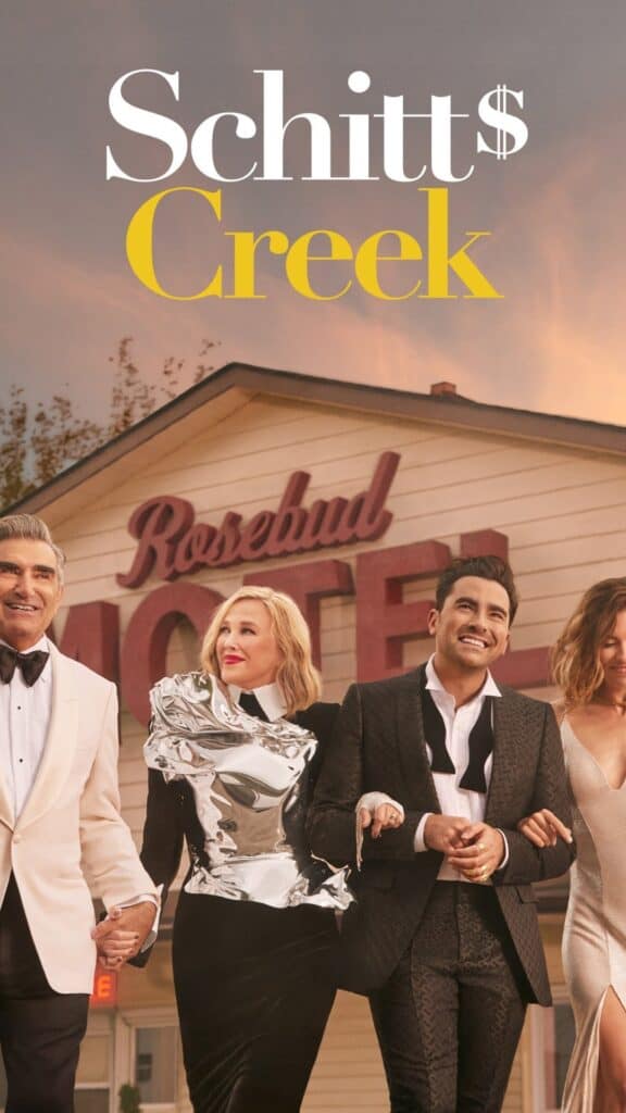 Schitt’s Creek cast poster featuring the Rose family dressed formally while walking together in front of the Rosebud Motel at sunset.