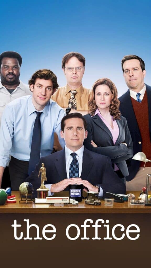 The Office cast poster featuring the Dunder Mifflin employees posed behind an office desk in a classic workplace comedy ensemble shot.