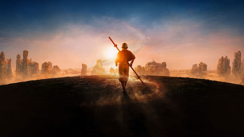 A lone Avatar character walking across a dusty landscape toward the rising sun while carrying a staff