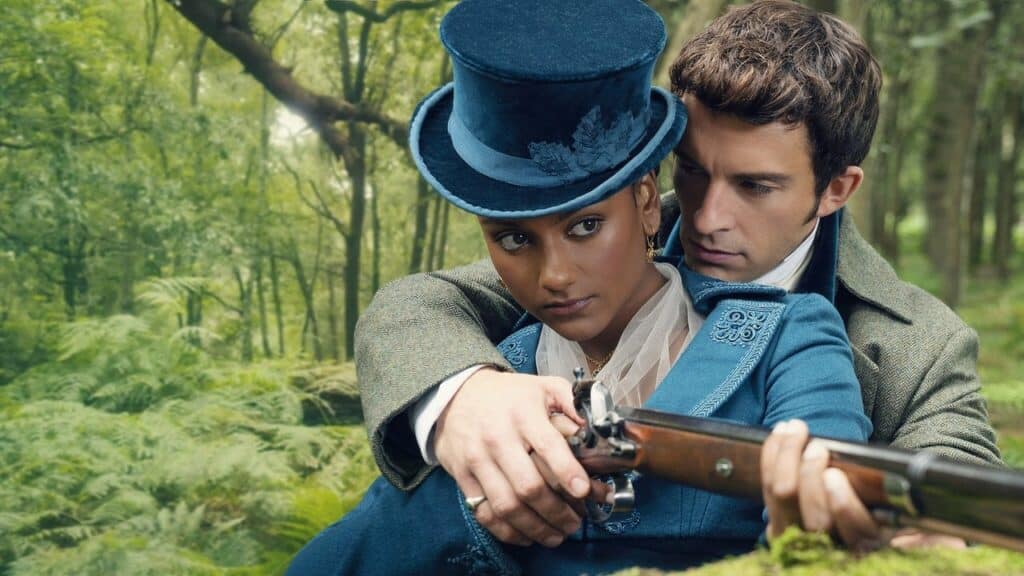 A woman in a blue Regency outfit aims a rifle in a forest while a man stands close behind her, guiding her posture with focused intensity.