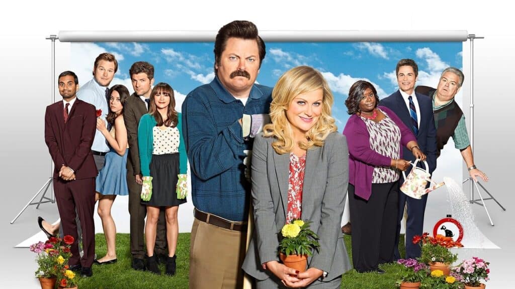 Promotional image of the Parks and Recreation cast standing together, with Leslie Knope at the center, representing the show’s warm and team-focused dynamic.