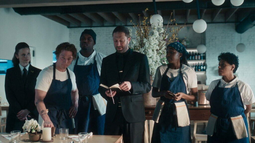 Carmy and the restaurant team listen closely during a serious meeting inside the newly designed dining space