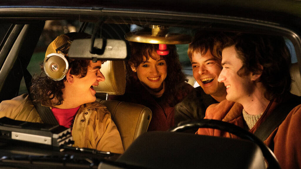 Four friends from Stranger Things laugh together inside a car, showing their close bond and friendship.
