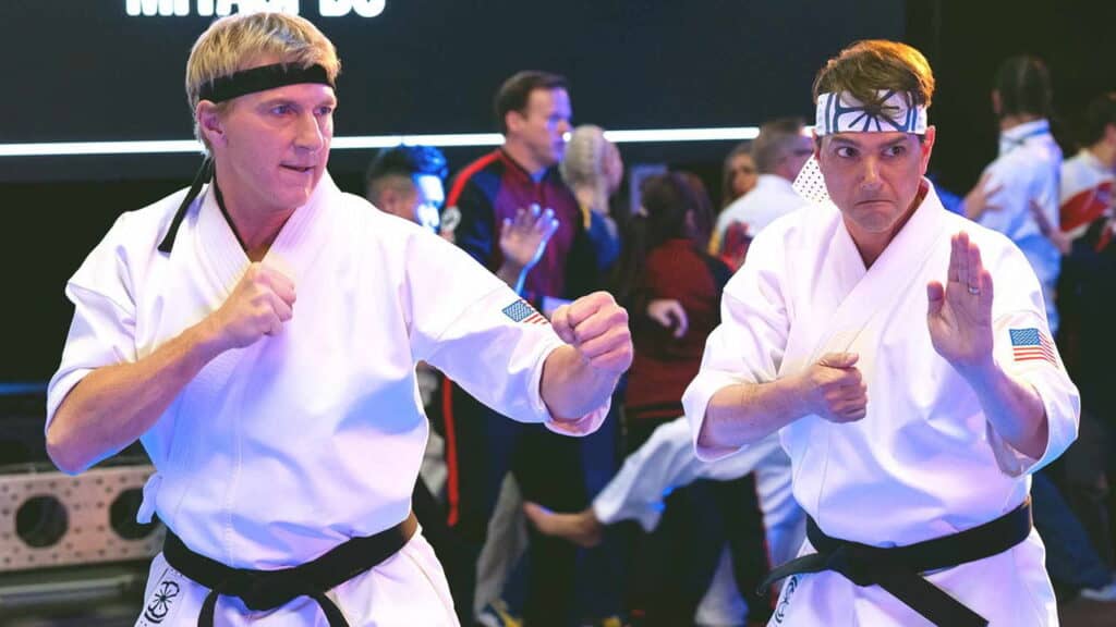 Johnny Lawrence and Daniel LaRusso facing each other in karate stances during a tournament scene in Cobra Kai