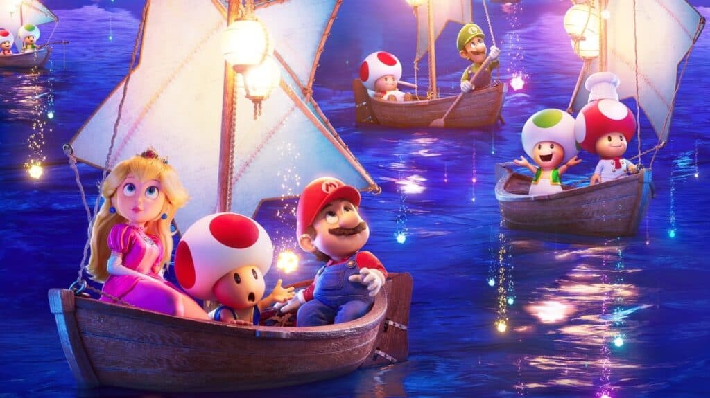 In a scene from "The Super Mario Galaxy Movie," Princess Peach, Mario, and a Toad sit in a small wooden sailboat at night. A large, glowing paper lantern hangs on the boat's mast, casting light. In the background, other sailboats with lanterns carry other characters, including Luigi and two Toads. The boats are sailing on a sparkling, dark blue ocean.