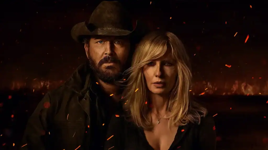 A dark, cinematic horizontal cast photo of Cole Hauser as Rip Wheeler in a cowboy hat and Kelly Reilly as Beth Dutton. They are looking directly forward, emerging from a shadow with floating fire sparks and embers, representing the high stakes of 'Dutton Ranch'.